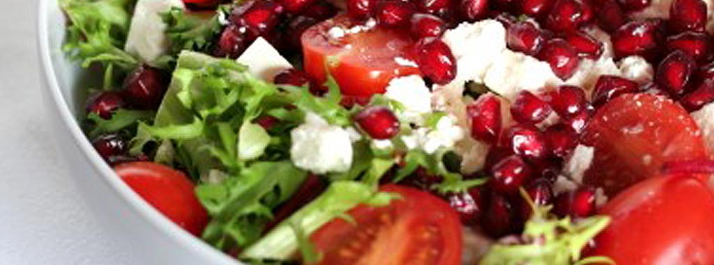 Fresh salad with pomegranate seeds, tomatoes, greens, and feta